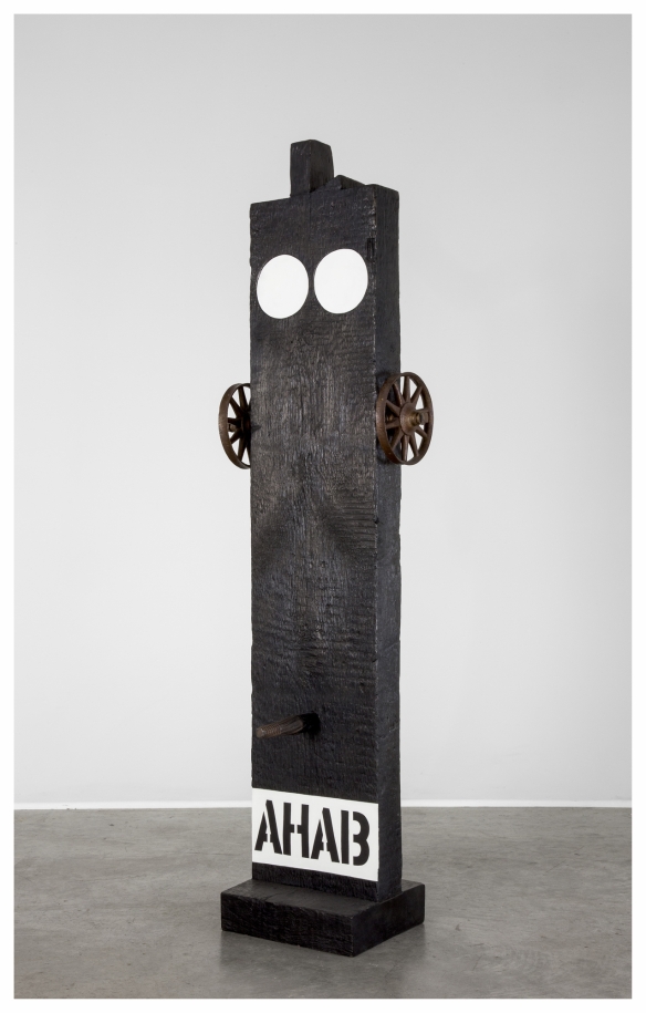 A black painted bronze beam beam with a haunched tenon on a black base. Across the bottom the work's title, Ahab, is painted in black stenciled letters against a white band of paint. Above the title is a peg. A small wheel has been attached to both the right and left side of the upper third of the sculpture. At the top of the sculpture are two white circles.