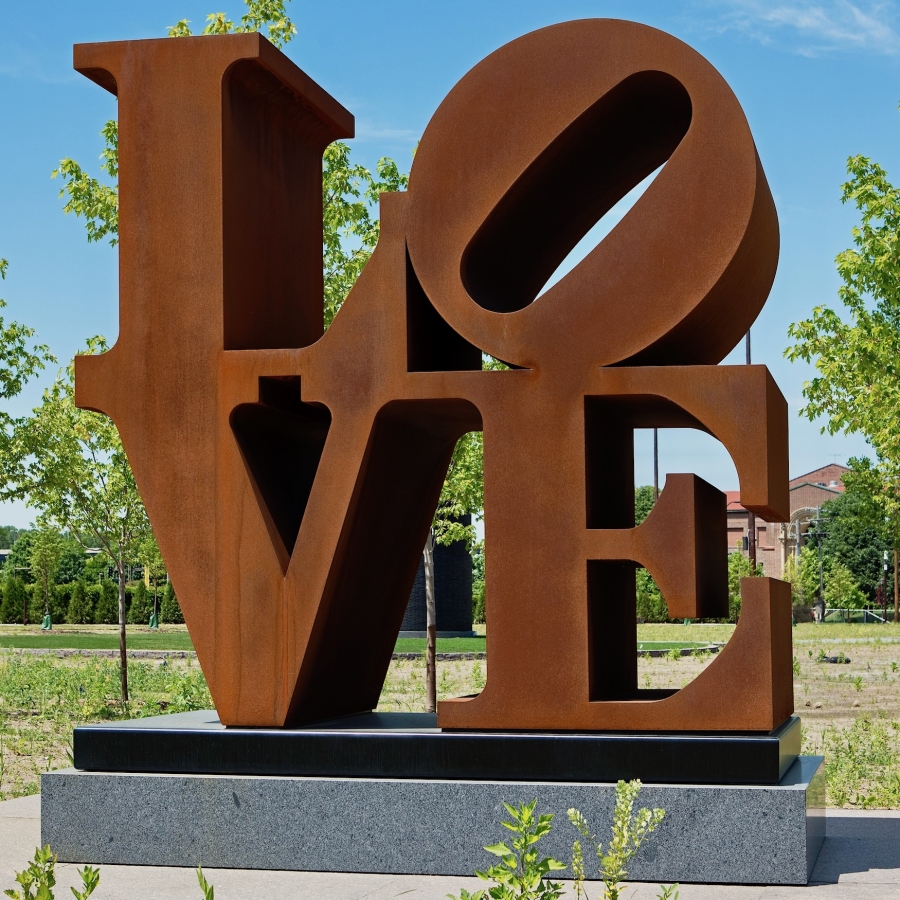 LOVE is a 96 by 96 by 48 inch Cor-Ten steel sculpture. The work consists of the letter "L" and a tilted letter "O" above the letters "V" and "E."