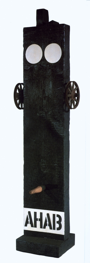 A sculpture consisting of a painted black wooden beam on a black wooden base. Across the bottom the work's title, Ahab, is painted in black stenciled letters against a white band of paint. Above the title is a wooden peg. A small wheel has been attached to both the right and left side of the upper third of the sculpture. At the top of the sculpture are two white circles.