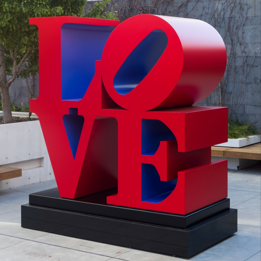 A 96 by 96 by 48 inch polychrome aluminum sculpture spelling love, consisting the letters L and a tilted letter O on top of the letters V and E. The outsides of the letters are red, and the insides are violet.
